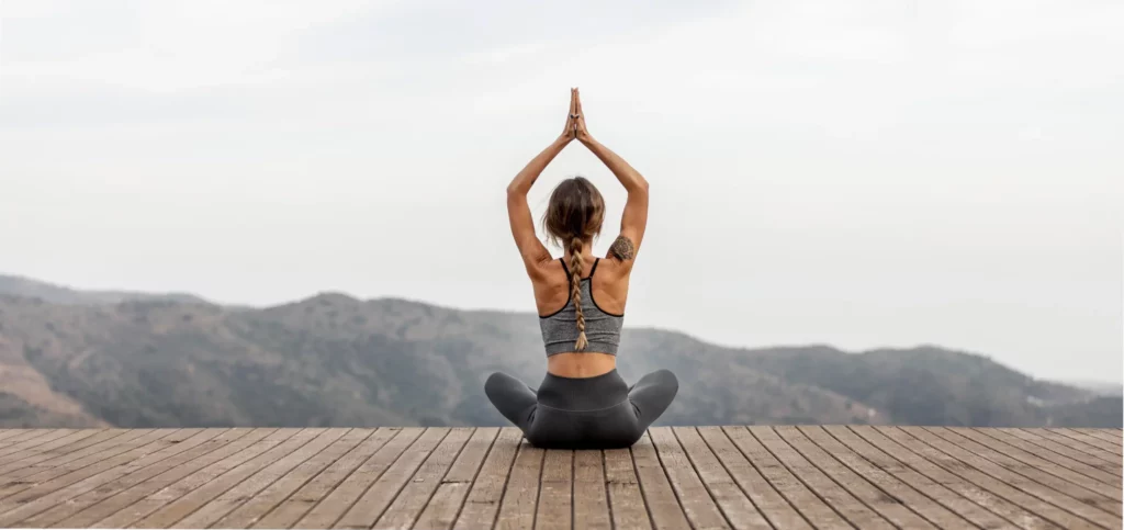 femme pratiquant le yoga en extérieur pour réduire le stress et protéger son vieillissement biologique