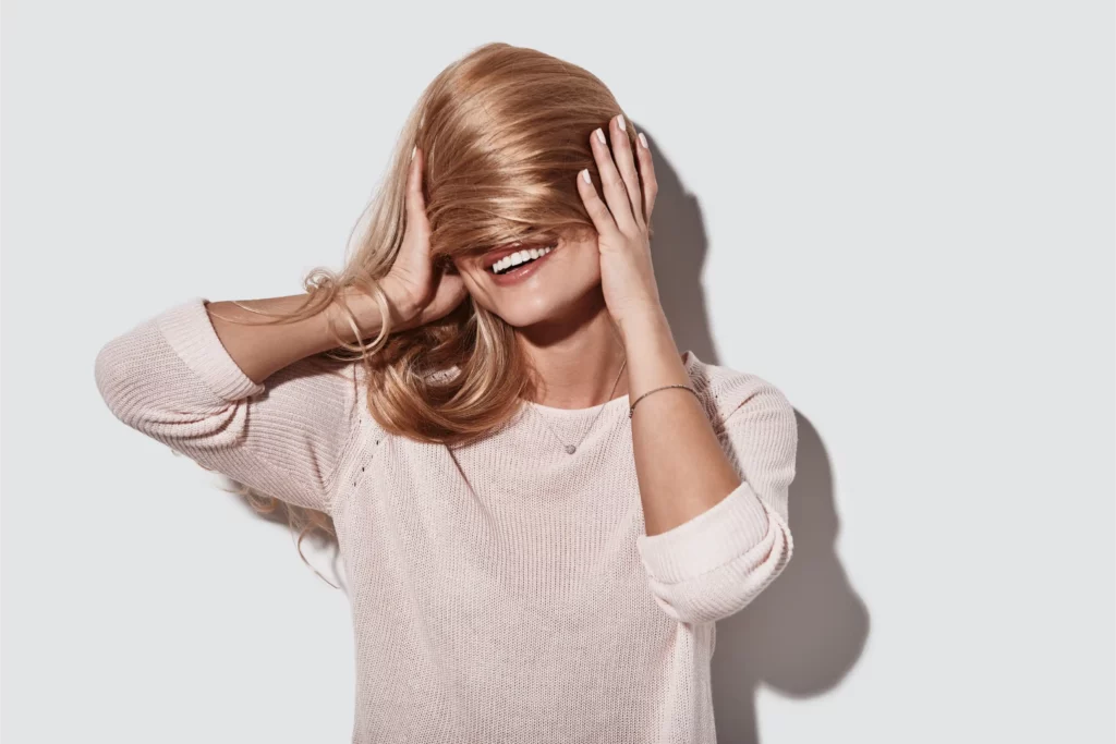 Jeune femme ajustant ses cheveux symbolisant les bienfaits dun complement alimentaire cheveux pour limiter la chute renforcer les racines et aider les cheveux fins
