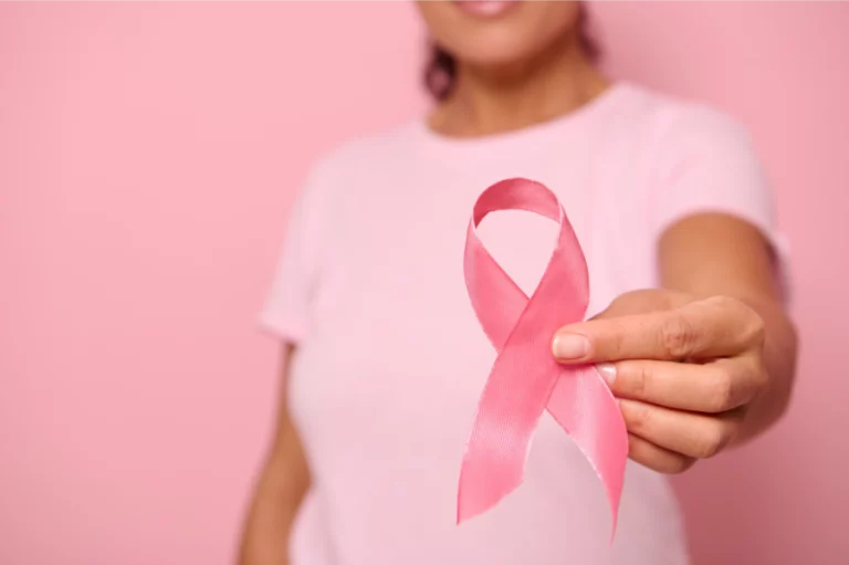 Femme tenant un ruban rose symbole d'Octobre Rose, illustrant la sensibilisation au cancer du sein et les enjeux de santé féminine après 40 ans